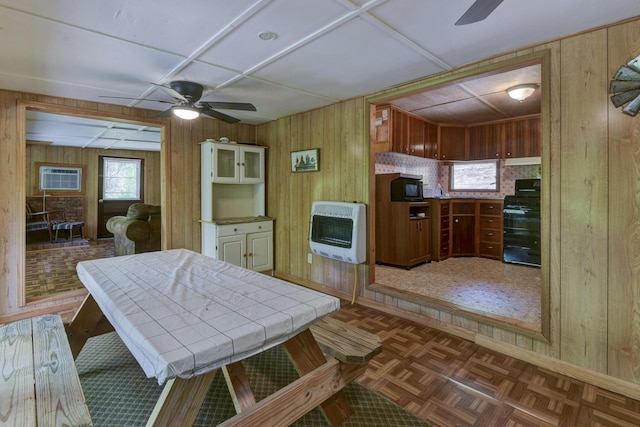 dining area with a ceiling fan, a wall mounted air conditioner, heating unit, baseboards, and wood walls
