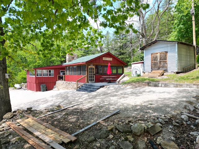 view of front of house featuring a chimney, an outdoor structure, and a storage shed