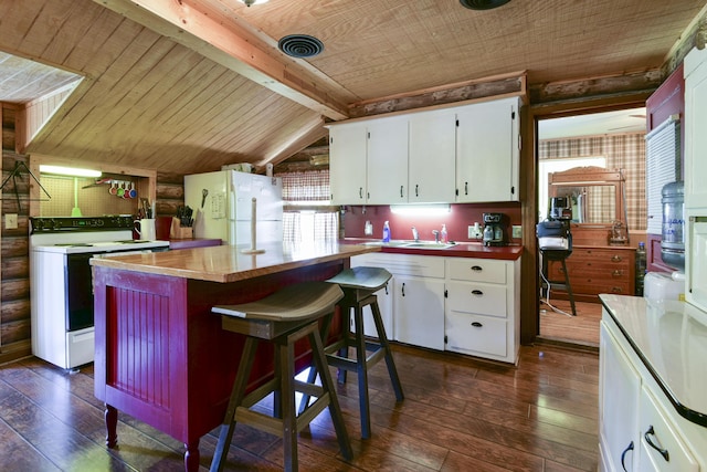 kitchen with white appliances, dark wood-style flooring, white cabinetry, a kitchen island, and vaulted ceiling with beams