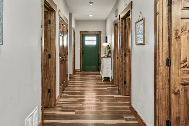 hallway with visible vents, wood finished floors, and baseboards