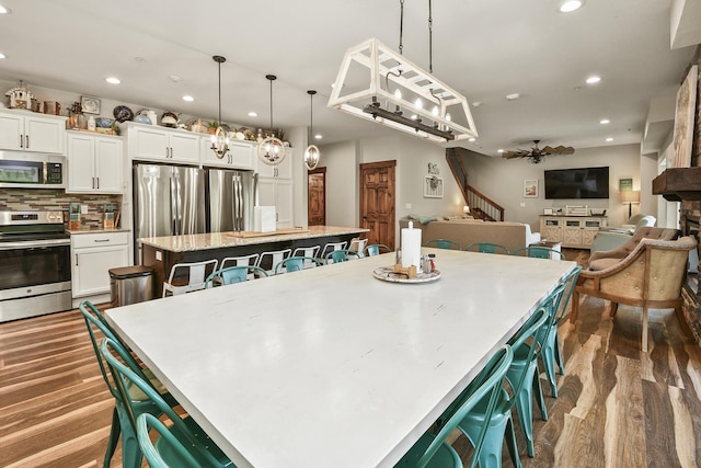 kitchen with white cabinets, a large island, stainless steel appliances, and dark wood-style flooring