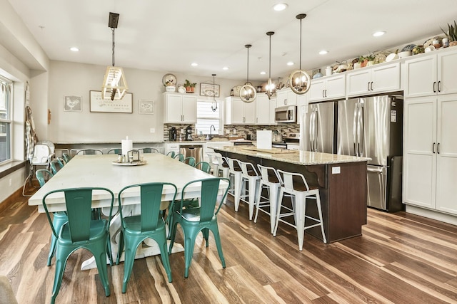 kitchen featuring a kitchen island, stainless steel appliances, a kitchen bar, and dark wood-style floors