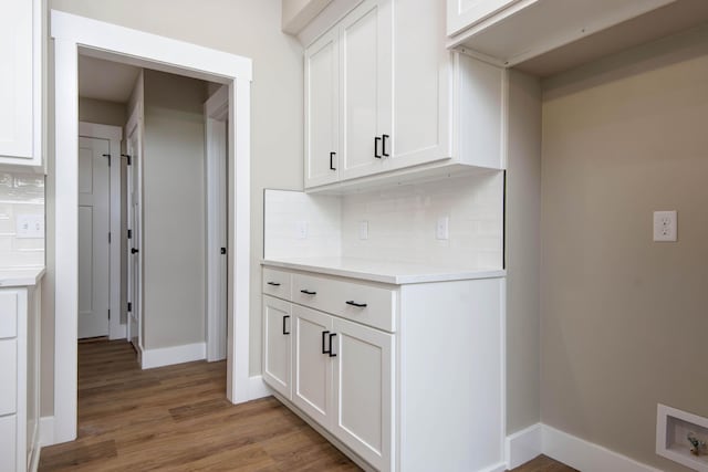 385 Plumtree Dr, Ozark, MO 65721 - kitchen with light wood-style flooring, decorative backsplash, light countertops, white cabinets, and baseboards