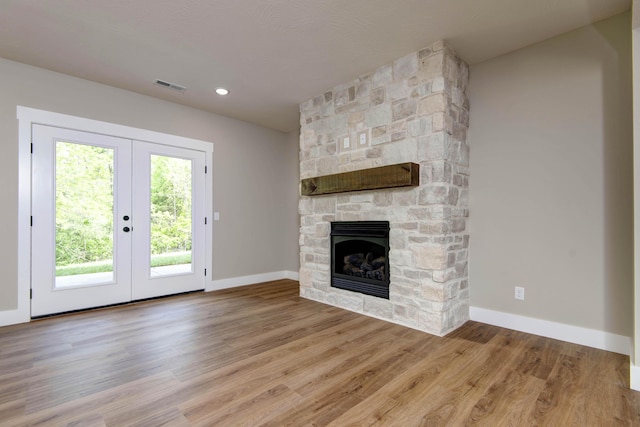 385 Plumtree Dr, Ozark, MO 65721 - unfurnished living room featuring french doors, baseboards, a stone fireplace, visible vents, and wood finished floors
