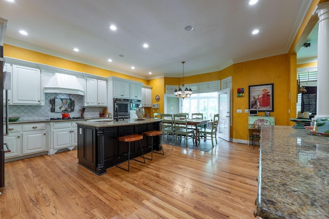 kitchen featuring light wood-type flooring, premium range hood, appliances with stainless steel finishes, and a kitchen bar
