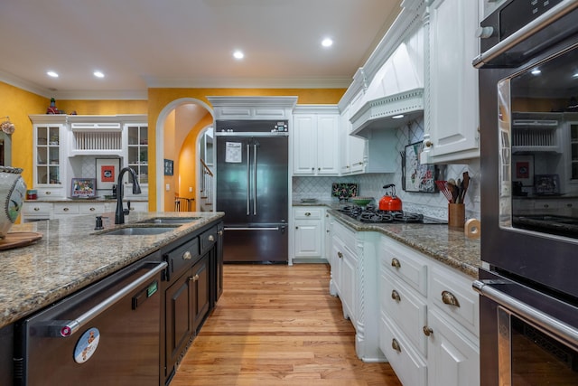 kitchen featuring a sink, stone countertops, appliances with stainless steel finishes, white cabinetry, and light wood-style floors