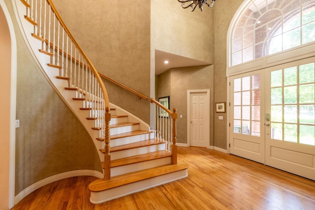 foyer with stairs, plenty of natural light, a high ceiling, and wood finished floors