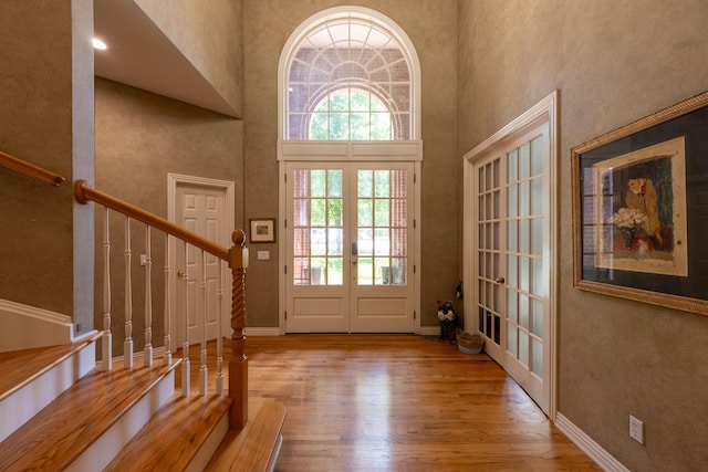 entryway with a high ceiling, french doors, plenty of natural light, and wood finished floors