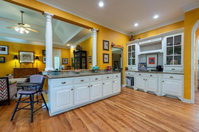 kitchen featuring light wood-type flooring, ornate columns, ceiling fan, glass insert cabinets, and white cabinets