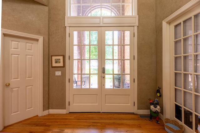 doorway to outside with baseboards, french doors, plenty of natural light, and wood finished floors