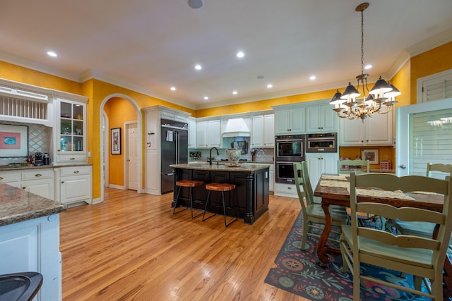 kitchen with premium range hood, tasteful backsplash, high end black fridge, a breakfast bar area, and an inviting chandelier