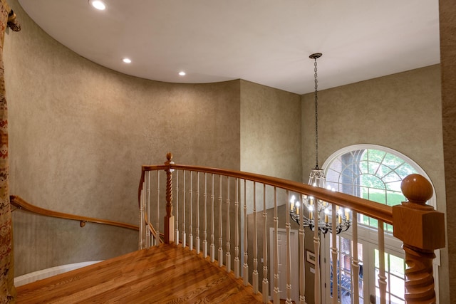 staircase featuring a notable chandelier, recessed lighting, a towering ceiling, and wood finished floors