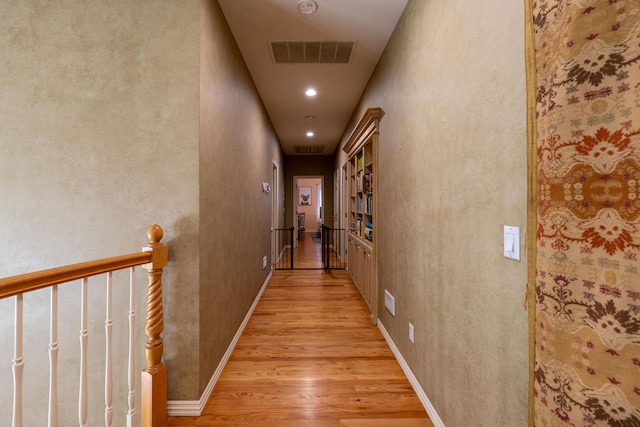 corridor featuring light wood-style flooring, baseboards, visible vents, and recessed lighting