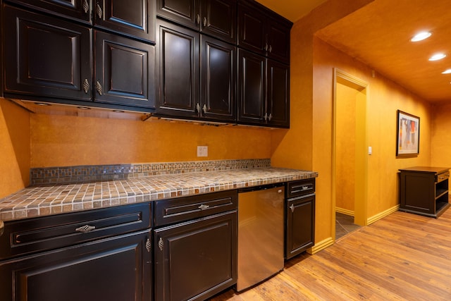 kitchen with light wood-style flooring, refrigerator, baseboards, tile countertops, and recessed lighting