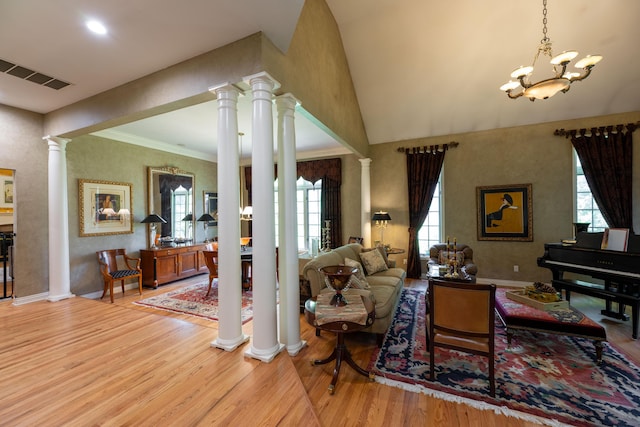 living room with baseboards, an inviting chandelier, visible vents, decorative columns, and wood finished floors