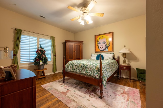 bedroom with baseboards, a ceiling fan, visible vents, and wood finished floors