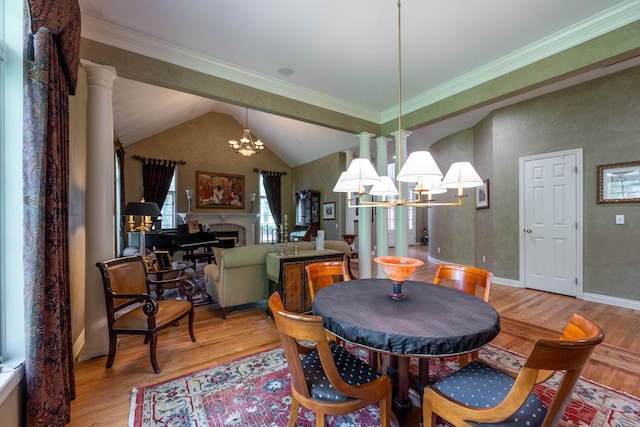 dining space featuring lofted ceiling, light wood-style floors, a chandelier, and ornate columns