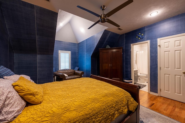 bedroom with lofted ceiling, connected bathroom, a ceiling fan, and wood finished floors