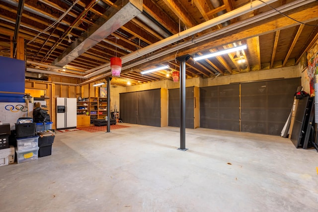 unfinished basement with white refrigerator with ice dispenser