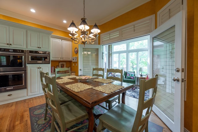 dining area with ornamental molding, an inviting chandelier, and light wood-type flooring