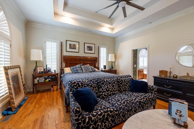 bedroom featuring wood finished floors, ornamental molding, visible vents, a ceiling fan, and a raised ceiling