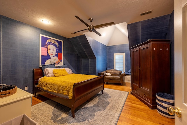 bedroom with vaulted ceiling, visible vents, light wood-style flooring, and a ceiling fan