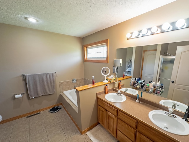 full bath featuring a bath, a textured ceiling, visible vents, and a sink