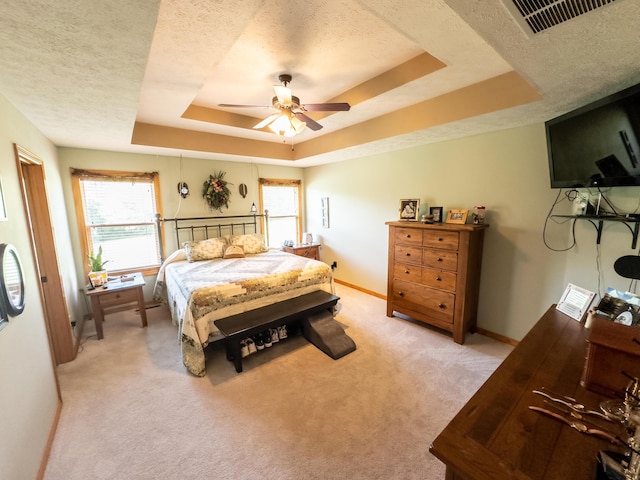 bedroom with a raised ceiling, multiple windows, visible vents, and a textured ceiling
