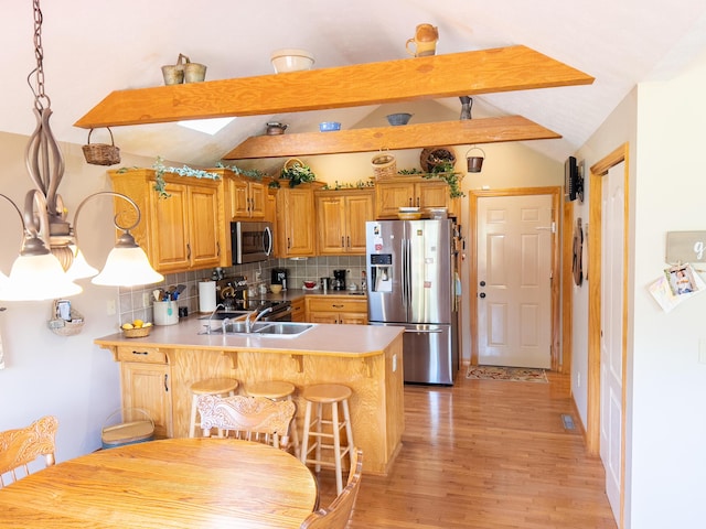kitchen featuring a peninsula, stainless steel appliances, light wood finished floors, decorative backsplash, and vaulted ceiling with beams