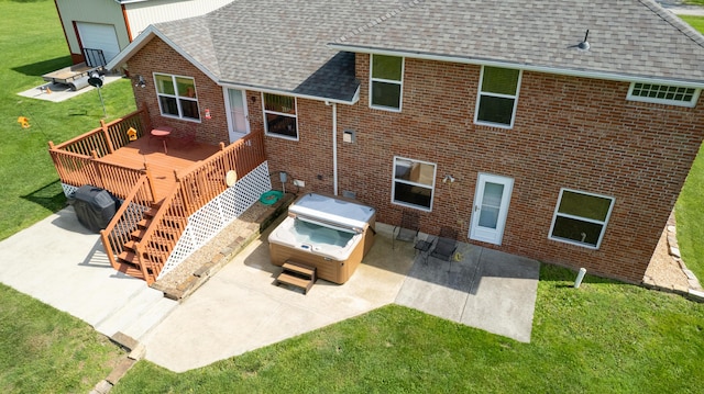 back of property with a hot tub, brick siding, a patio, a wooden deck, and roof with shingles