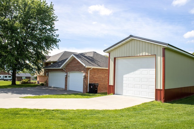 view of front of home featuring aphalt driveway, an outbuilding, brick siding, and a front yard