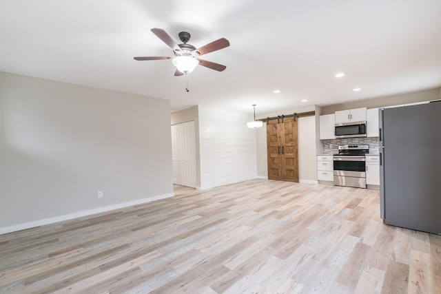 unfurnished living room featuring light wood finished floors, a ceiling fan, baseboards, a barn door, and recessed lighting