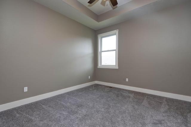 unfurnished room featuring ceiling fan, baseboards, a raised ceiling, and dark carpet