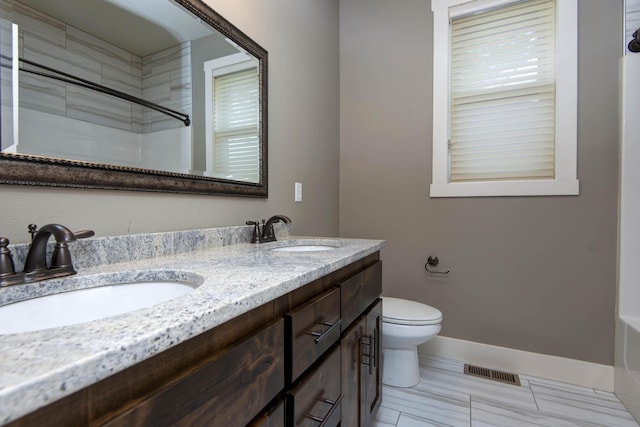 bathroom with double vanity, toilet, visible vents, and a sink