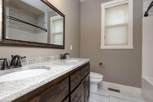 bathroom featuring toilet, visible vents, a sink, and double vanity