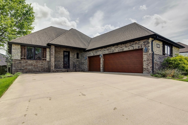 view of front of home featuring an attached garage, concrete driveway, brick siding, and roof with shingles
