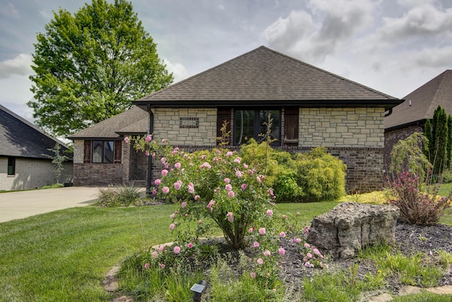 view of front of home featuring a front lawn, brick siding, roof with shingles, and stone siding