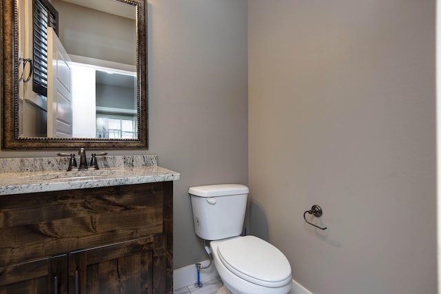 half bath with baseboards, vanity, and toilet