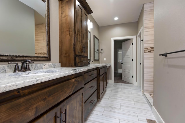 bathroom with double vanity, baseboards, and a sink