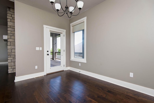unfurnished dining area featuring dark wood finished floors, visible vents, baseboards, and a notable chandelier