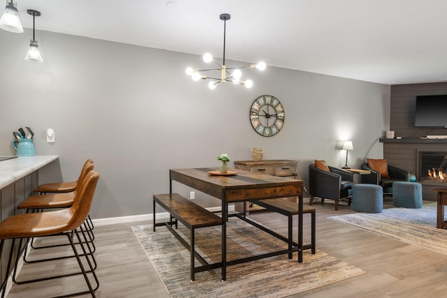 112 Overlook Dr Unit 2, Branson, MO 65616 - dining area with light wood-style floors, a warm lit fireplace, baseboards, and a notable chandelier