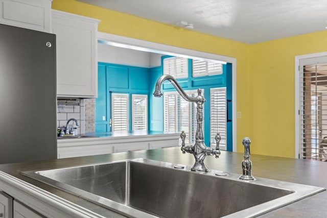 kitchen with white cabinetry, backsplash, and a sink