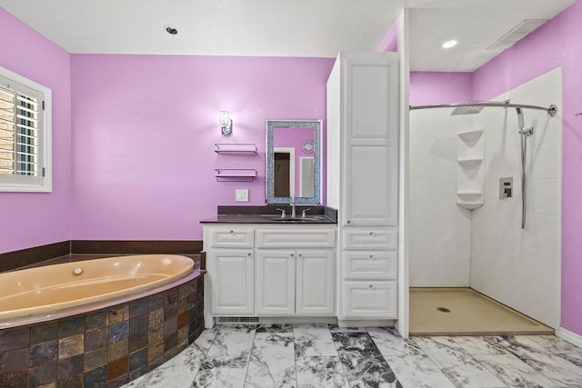 bathroom with marble finish floor, vanity, visible vents, a garden tub, and a tile shower