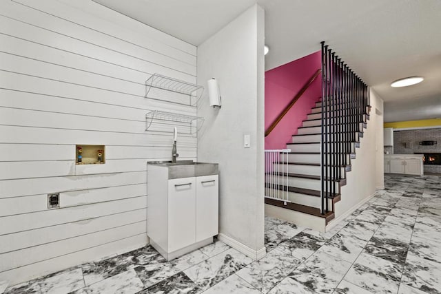stairway featuring baseboards, marble finish floor, and wooden walls