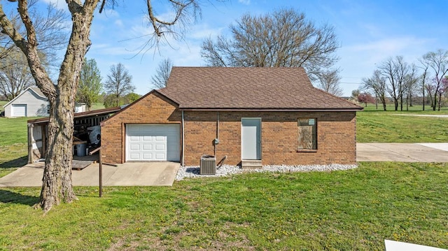 exterior space featuring a garage, a lawn, central air condition unit, brick siding, and roof with shingles