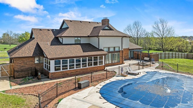 rear view of house with a chimney, a patio area, brick siding, and roof with shingles