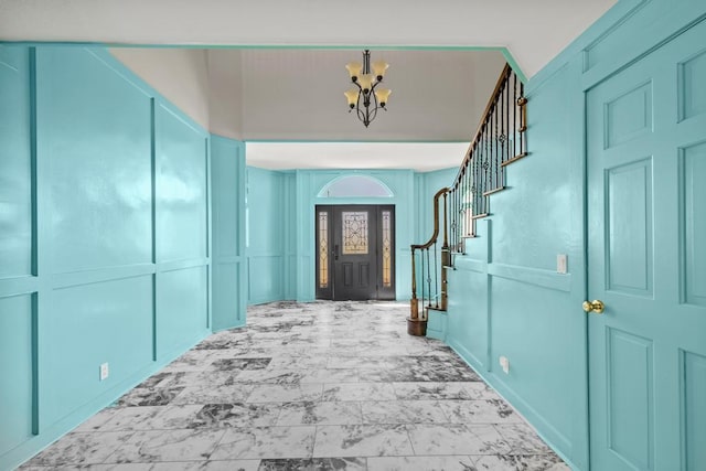 hall featuring a chandelier, a decorative wall, stairway, and marble finish floor