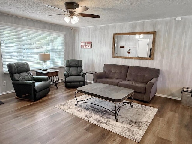living room featuring a textured ceiling, baseboards, a ceiling fan, and wood finished floors