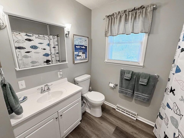 bathroom featuring toilet, wood finished floors, visible vents, baseboards, and vanity