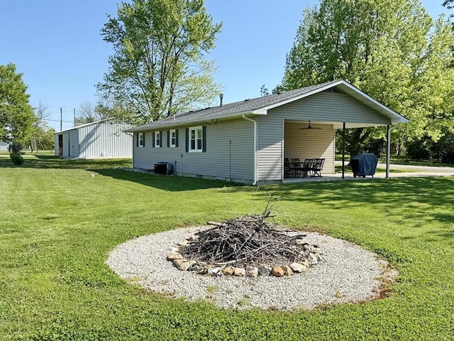 back of house featuring a lawn, ceiling fan, an outdoor fire pit, a patio area, and central AC unit